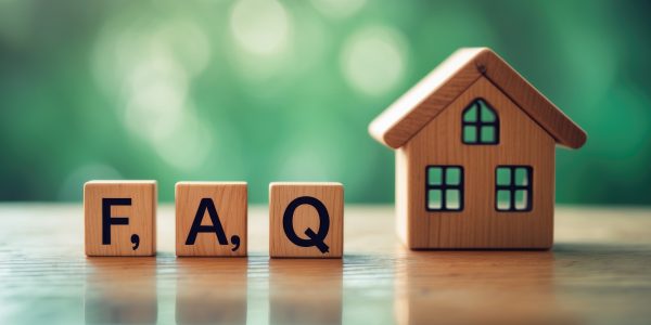 Close-up of a FAQ text block alongside a toy wooden house on a wooden table.