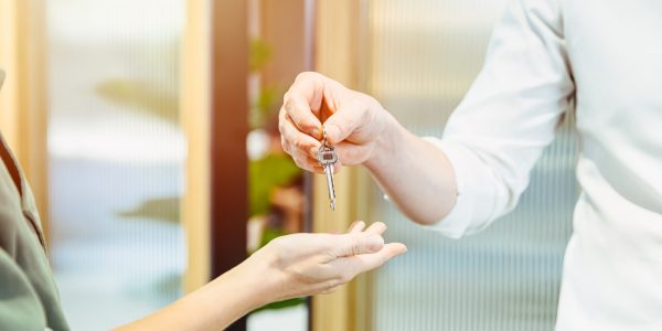 Male hand giving return apartment or home room key to women.